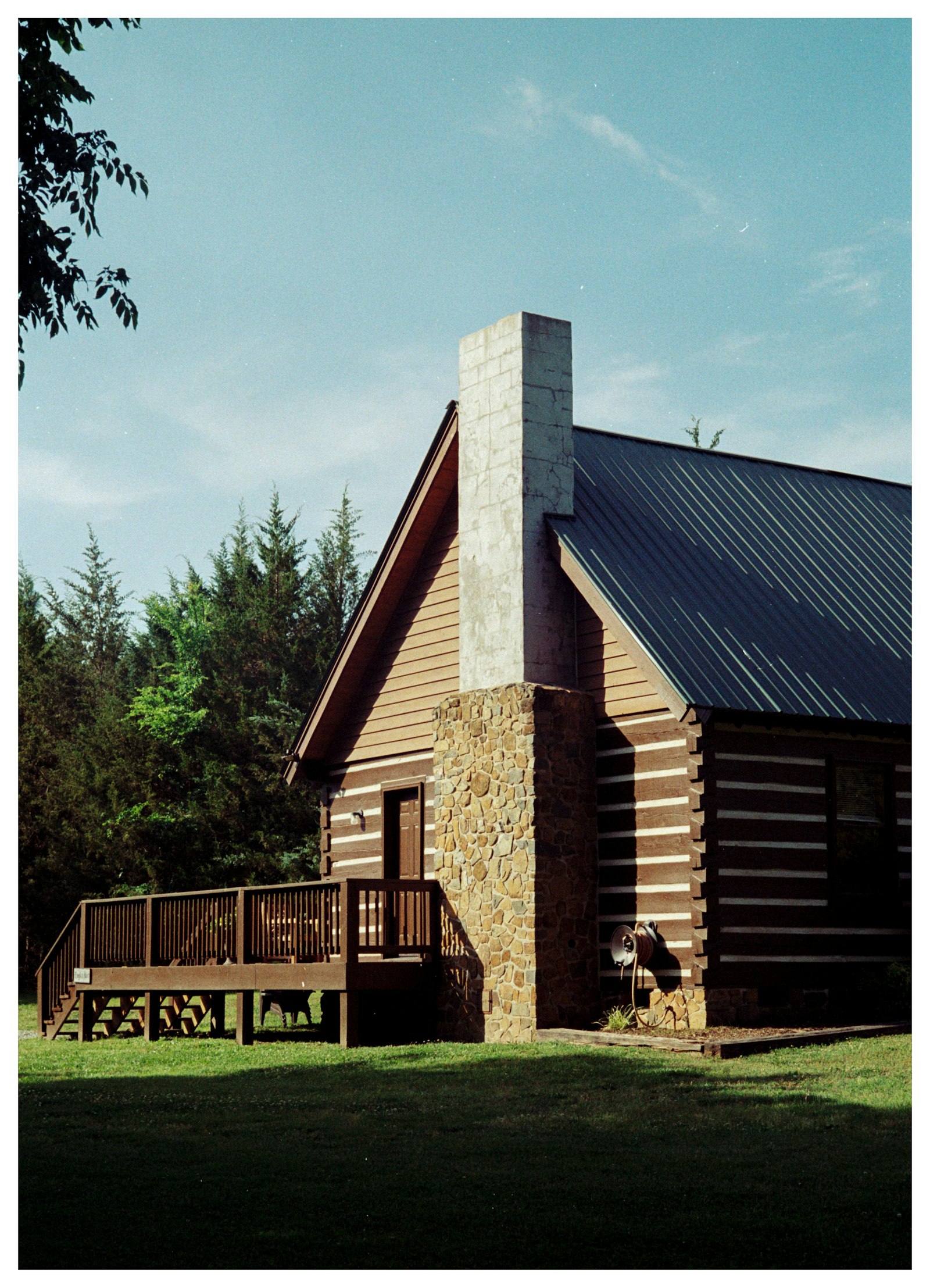 Timber-frame log cabin porch with a stone chimney in the mountains